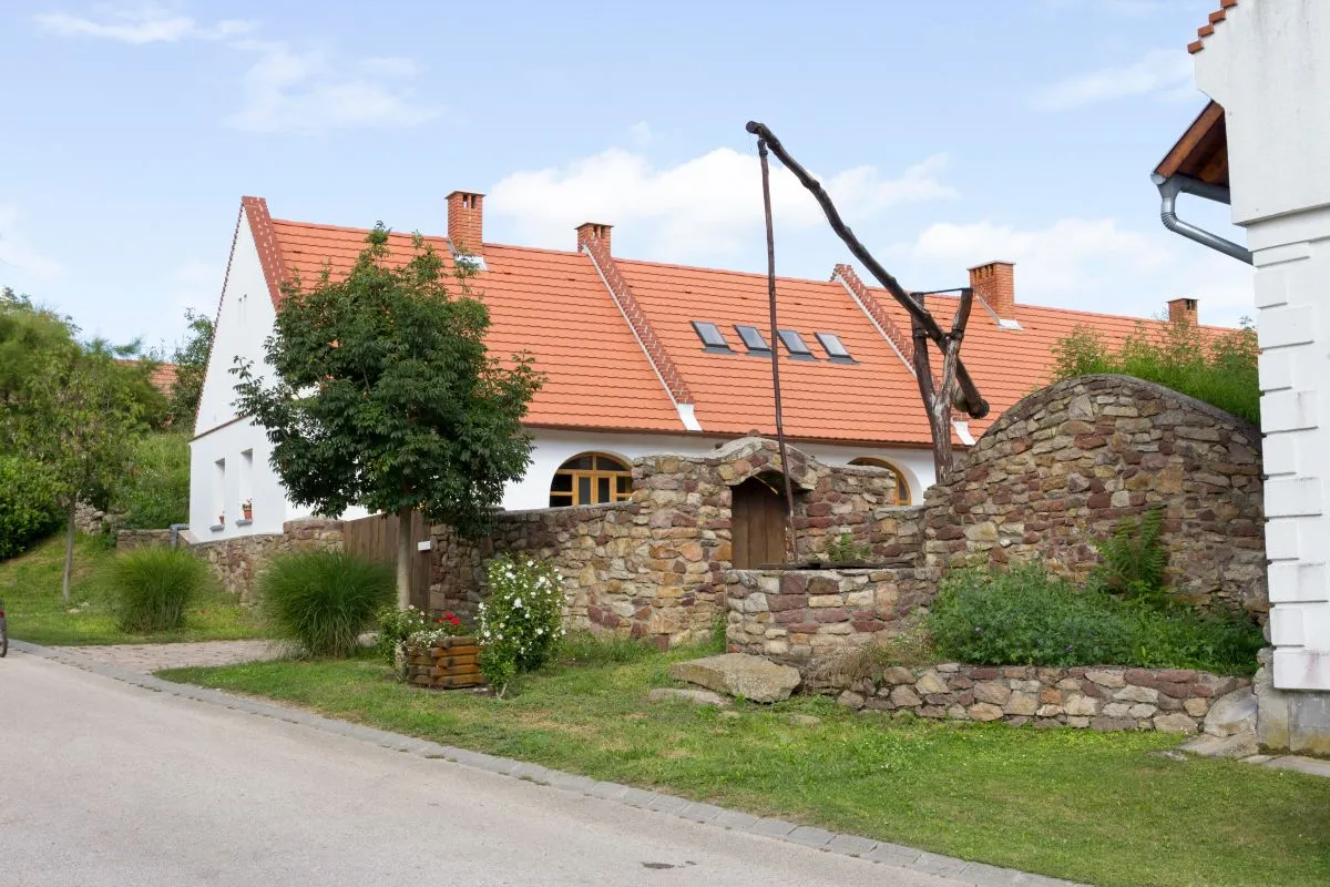 Falusi utcakép Kékkúton, virágos kertekkel és terméskő kerítésekkel.