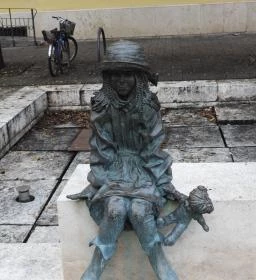 Kövön ülő kislány babával