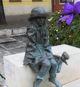 Kövön ülő kislány babával