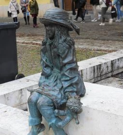 Kövön ülő kislány babával