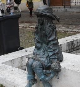 Kövön ülő kislány babával