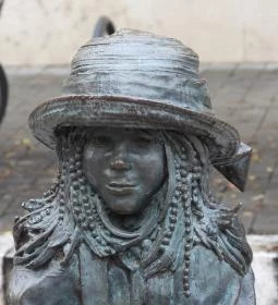 Kövön ülő kislány babával